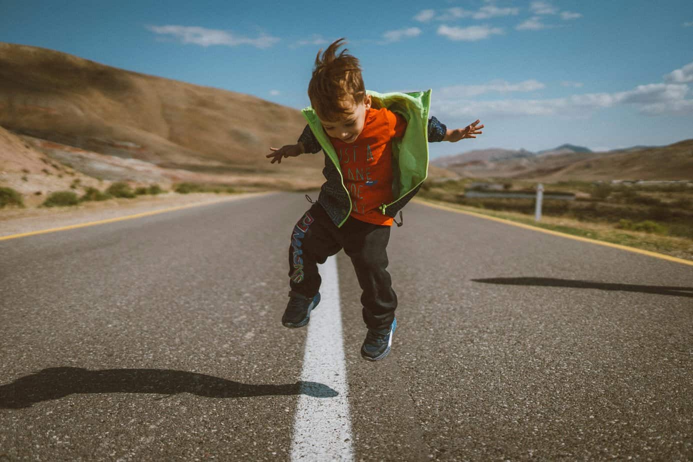 coordinating child custody across state lines represented by image of child jumping over a line on a road