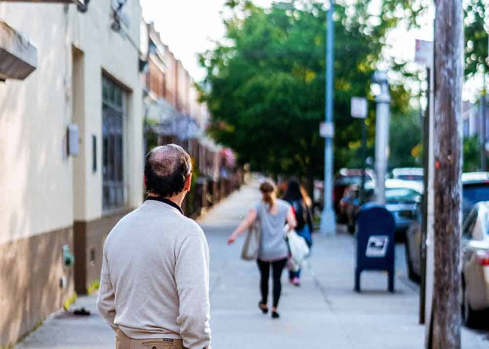 A woman carrying groceries, walking away from a man staring at her to represent suddenly divorced syndrome